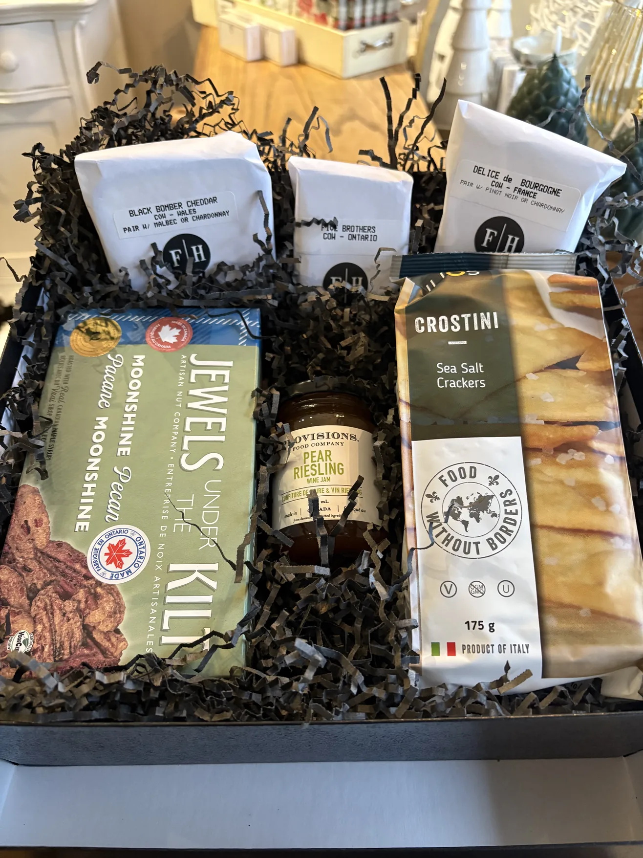 Gift box with wrapped artisan cheeses, crostini, preserves and candied pecans